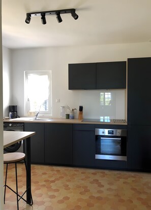 Eine moderne Küche mit Backofen, einer Kaffeemaschine und einem Fenster für natürliches Licht.