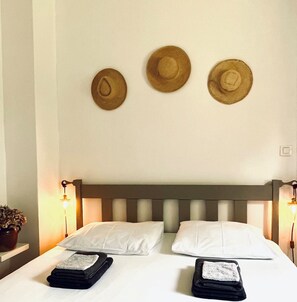 A bed with two pillows, a headboard, and three hats on the wall. - Holiday Home 'Le Perroudier' with Panoramic View of the Dordogne Valley (Vitrac)