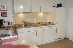 A compact kitchen with white cabinets, a countertop, a sink, and a stove. - House Castle Romance (Cochem)