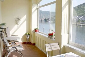 A room with a view of a river, a table, chairs, and potted plants. - House Castle Romance (Cochem)