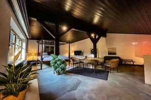 Una habitación amplia con techo alto, un comedor con mesa y sillas, y un televisor.