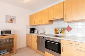 A modern kitchen with wooden cabinets, a microwave, a coffee maker, and a dishwasher. - Holiday apartment with 2 bedrooms (Norddeich)
