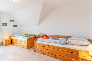 A bedroom with a loft bed, wooden drawers, a bedside table, and a lamp. - Holiday apartment with 2 bedrooms (Norddeich)