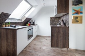 A modern kitchen with a skylight, wooden cabinets, and a built-in oven. - Holiday apartment with 2 bedrooms (Norderney)