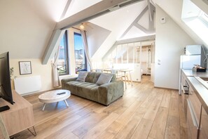 A modern loft apartment with a high ceiling, a sofa, a dining table, and a kitchen area. - Cozy and bright loft in the town center by Groom* (Guidel)