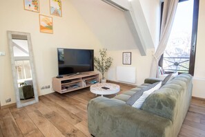 A living room with a television, a sofa, a coffee table, and a plant. - Cozy and bright loft in the town center by Groom* (Guidel)