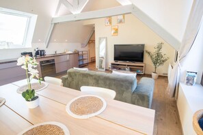Een modern interieur met een eethoek, bank, televisie en keuken.