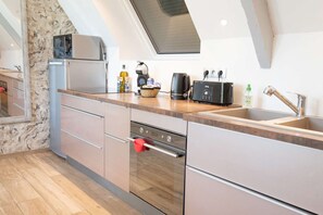 Een moderne keuken met een inbouwoven, koffiezetapparaat en broodrooster.