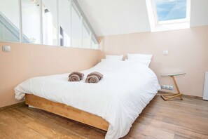 Een slaapkamer met een houten bedframe, wit beddengoed en een klein nachtkastje.