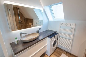 Een moderne badkamer met een vrijstaand wastafelmeubel, een inloopdouche en een ingebouwde wasmachine.