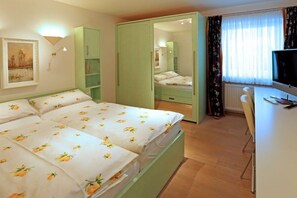 Ein Schlafzimmer mit Bett, Kleiderschrank, Schreibtisch und Fernseher.