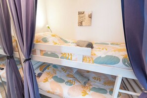 Ein Stockbett mit einem gemusterten Bettbezug, ein Wandbild und Vorhänge.