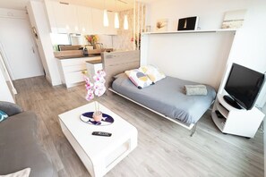 A modern bedroom with a bed, bedside table, and a TV stand. - Beautiful Studio for 4 people with 180° sea view by Groom* (Ploemeur)