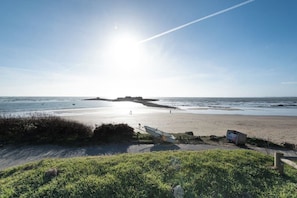 Ein Strand mit sandigem Ufer, einer grasbewachsenen Vordergrund und einem klaren Himmel.