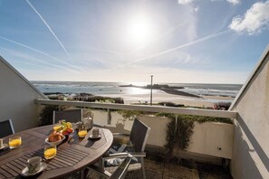 Un balcone con tavolo apparecchiato per la colazione con vista sulla spiaggia.