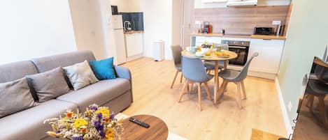 A modern apartment with a living area, a dining table, and a kitchenette.