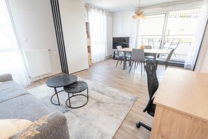 Ein modernes Wohnzimmer mit einer Couch, einem runden Couchtisch und einem Essbereich mit Stühlen und einem Tisch.