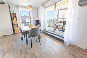 Een eetgedeelte met een tafel en stoelen, een boekenkast en een grote schuifdeur die uitkomt op een terras.