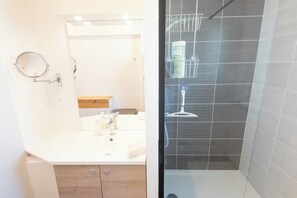 Een badkamer met een wit aanrecht, een spiegel en een douchecabine met een glazen deur.