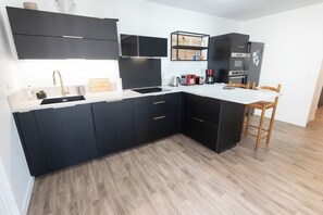 Eine moderne Küche mit schwarzen Schränken, einer Holzarbeitsplatte und einem eingebauten Backofen.