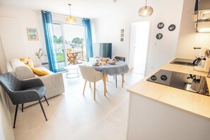 A modern kitchen with a dining area, a sofa, and a view to the outside. - Beautiful Brand-New 1-Bedroom Apartment – ​​View of Lorient Harbor – by Groom* (Lorient)