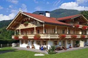 A traditional Alpine-style building with a red-tiled roof, multiple balconies, and a well-maintained garden. - Zugspitze in the Grasegger holiday home (Garmisch-Partenkirchen)