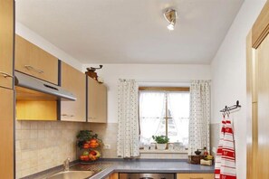A kitchen with a window, a sink, cabinets, and a countertop with fruits. - Wank in the Grasegger holiday home (Garmisch-Partenkirchen)