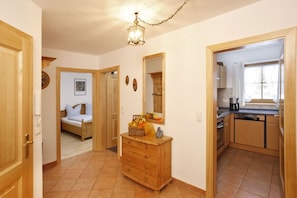 A room with a bed, a wooden dresser, a mirror, and a kitchen area with cabinets and a stove. - Wank in the Grasegger holiday home (Garmisch-Partenkirchen)