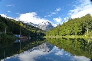 A calm lake with a mountain in the background, surrounded by dense forest. - At the spa park - Apartment 1 - 60 sqm (Garmisch-Partenkirchen)