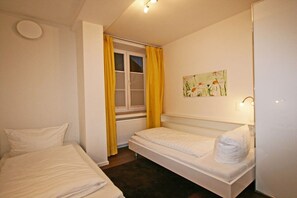 A small, single-bed room with a window, a radiator, and a painting on the wall. - At the spa park - Apartment 1 - 60 sqm (Garmisch-Partenkirchen)