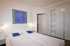 A hotel room with a bed, a wardrobe, and a painting on the wall. - At the spa park - Apartment 1 - 60 sqm (Garmisch-Partenkirchen)