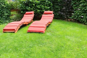 A row of sun loungers with red cushions in a grassy garden area. - ||-------------------------------House of Heaven--------------------------|| (Oberammergau)