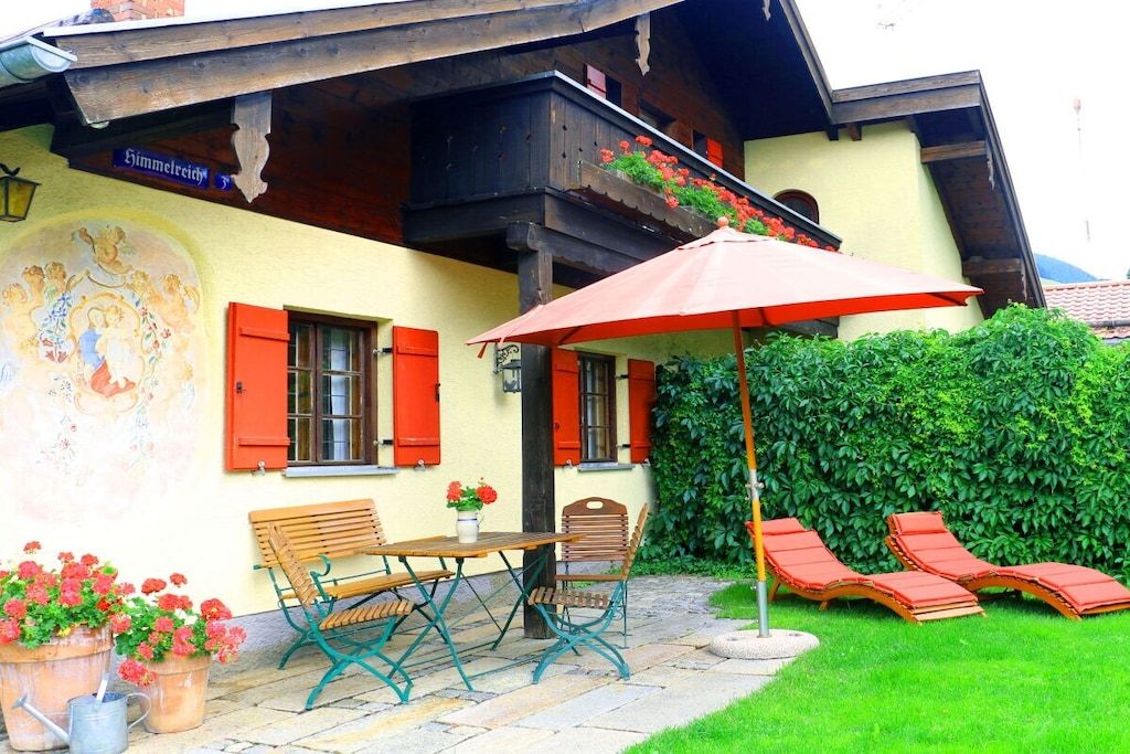 A traditional chalet with a dining area, outdoor seating, and a mural.