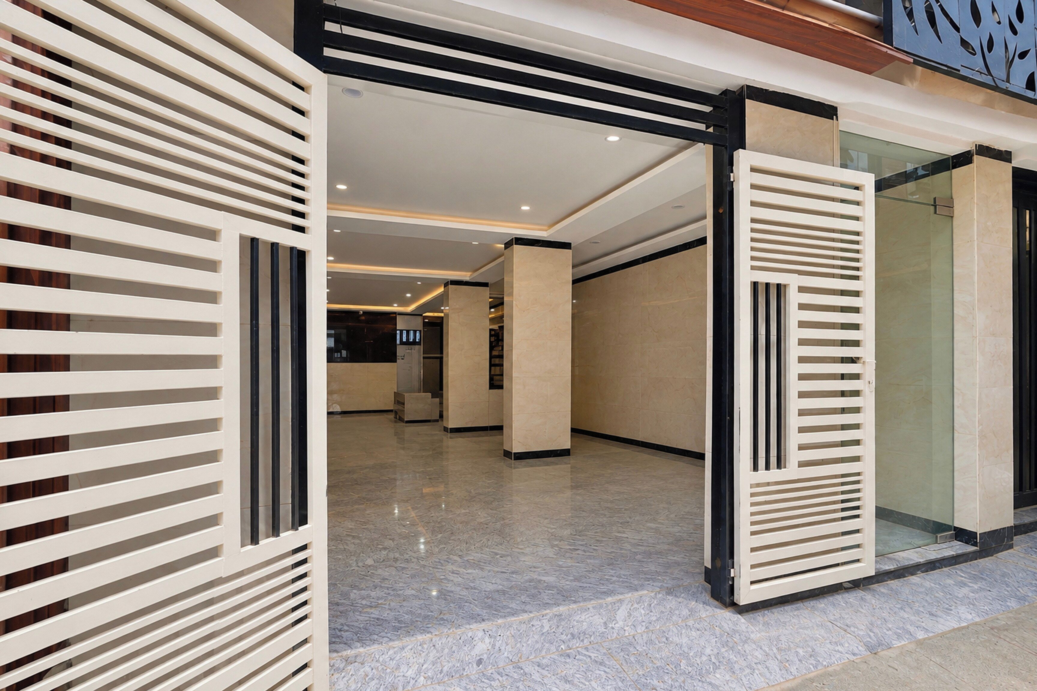 A modern interior with a corridor leading to a reception area, featuring a glass door, a reception desk, and a seating area.