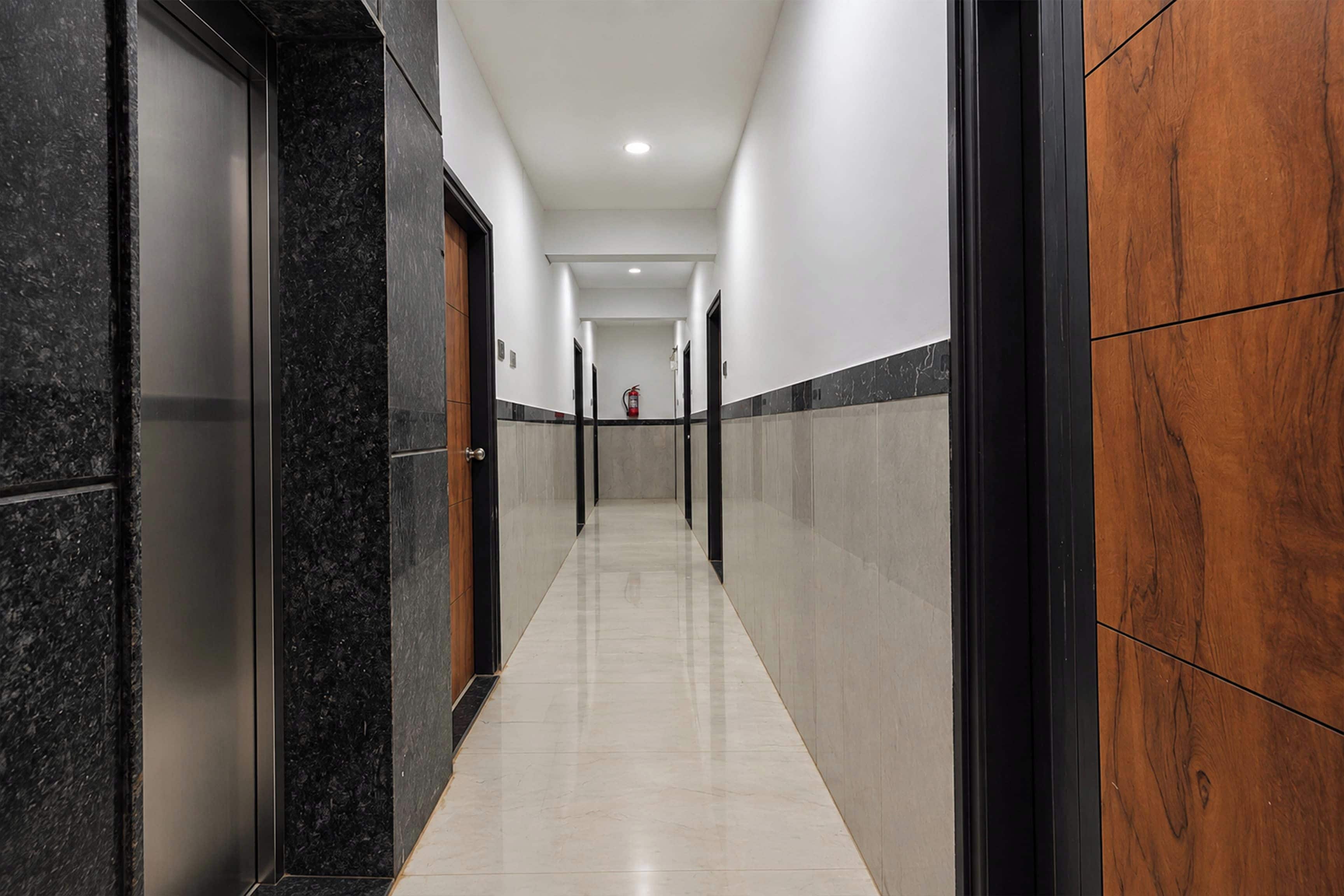 A corridor with a marble floor, black and white walls, and wooden paneling on one side.