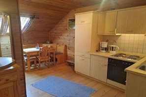 A wooden interior with a kitchen area, including cabinets, a stove, and a dining table with chairs.