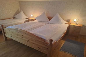 A wooden bed with a headboard, two bedside tables with lamps, and a small rug on the floor.