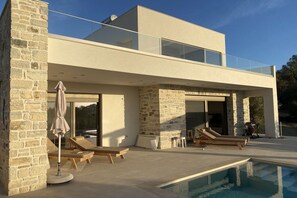 A modern two-story house with a swimming pool, stone walls, and a glass balcony. - Holiday home in Pitsidia with swimming pool (Pitsidia)