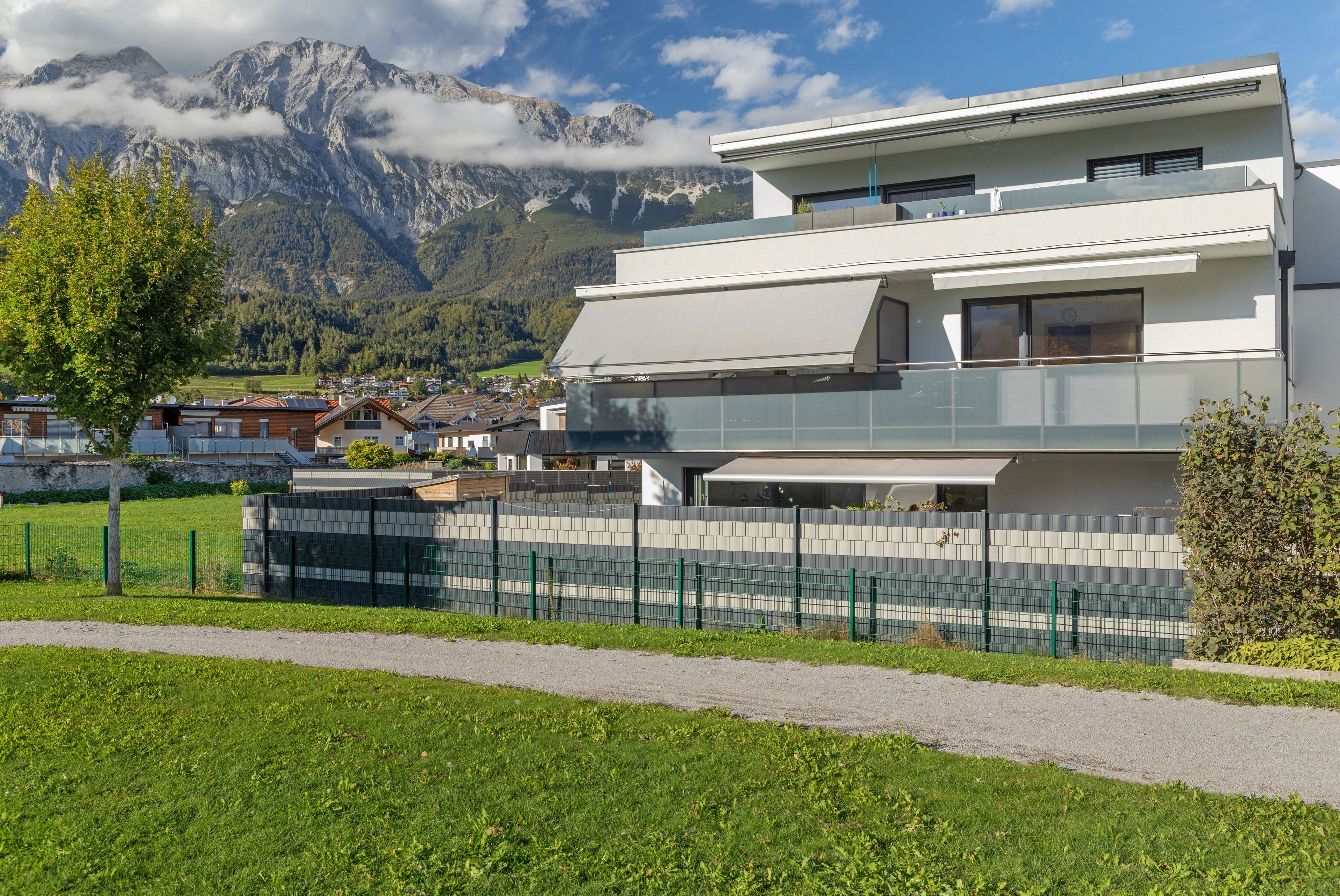 Ein modernes Gebäude mit Flachdach, großen Fenstern und einem Balkon.
