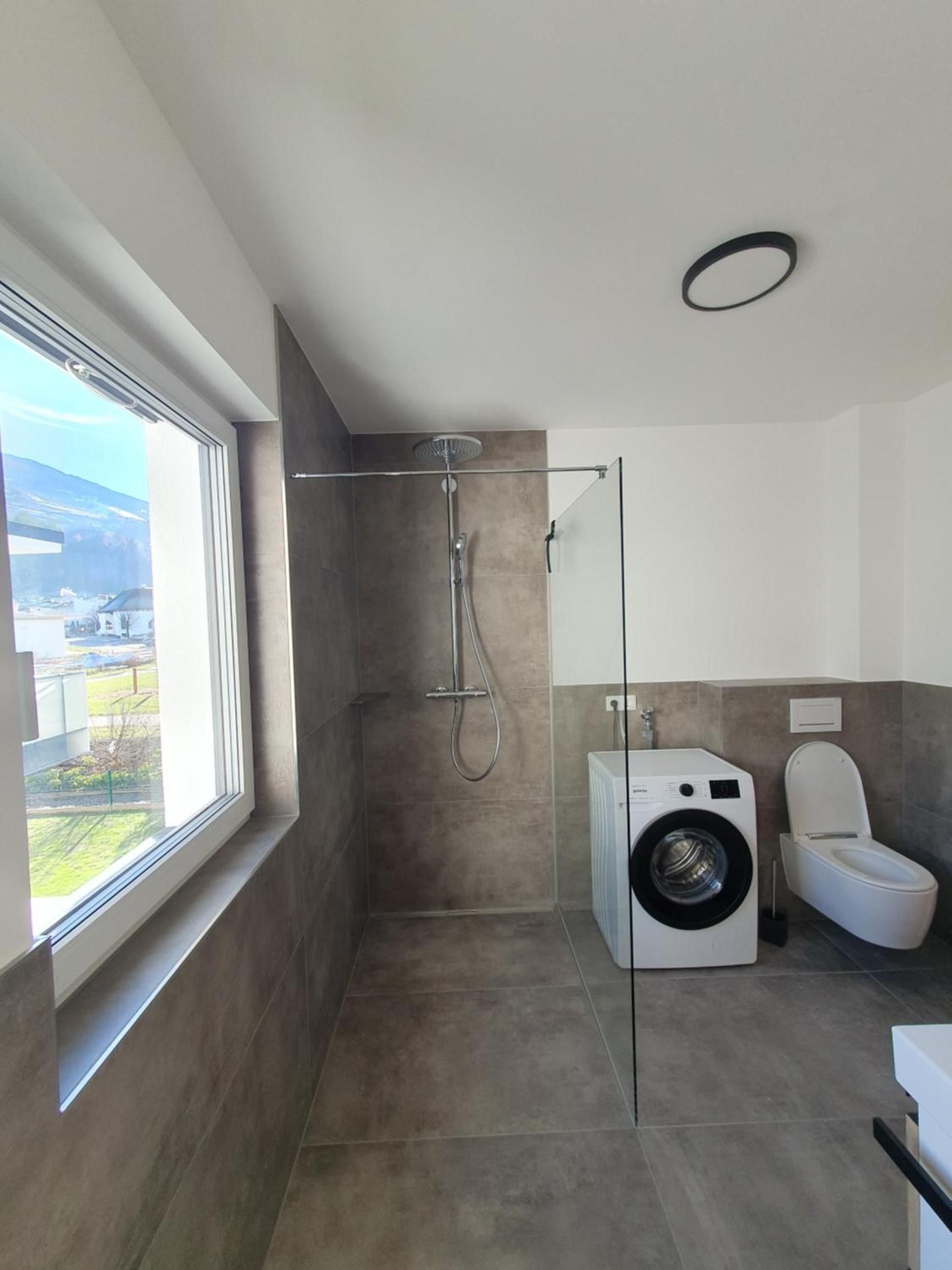 Ein modernes Badezimmer mit Duschkabine, Waschmaschine und Toilette.