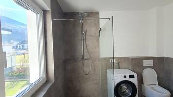 Ein modernes Badezimmer mit Duschkabine, Waschmaschine und Toilette.