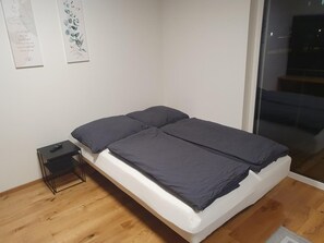 Un dormitorio con una cama individual, una mesita de noche pequeña y un televisor de pared.