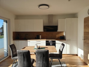 A modern kitchen with white cabinets, a wooden countertop, and a dining area with a table and chairs.