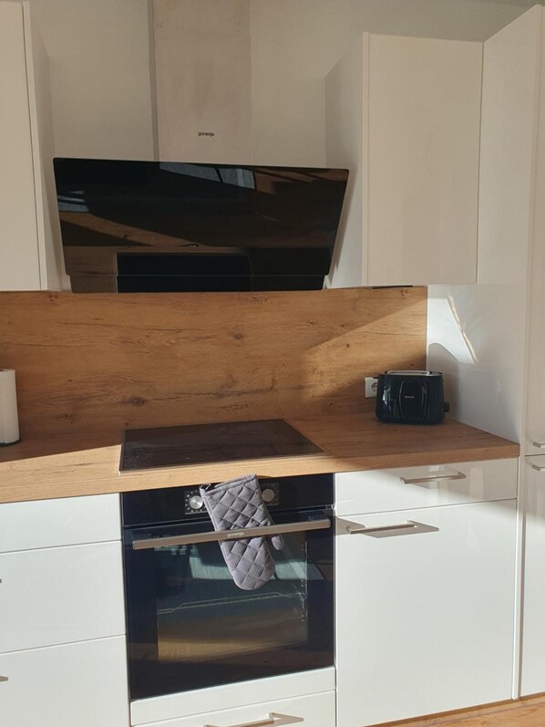 Eine Küche mit einer Holztischplatte, einem Toaster und einem aufgehängten Topflappen.