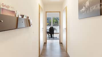 A hallway with a door leading to a balcony with outdoor seating.