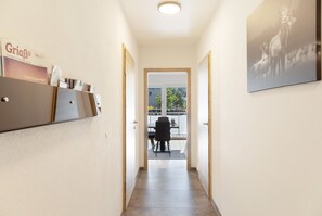 A hallway with a door leading to a balcony with outdoor seating.