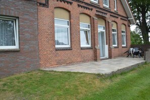 A two-story brick building with a front porch and a door. - Holiday apartment with 2 bedrooms (Neuschoo)