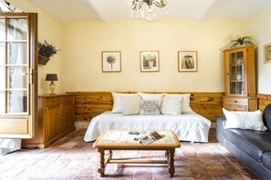 A bedroom with a bed, a wooden cabinet, a coffee table, and a sofa. - Gite Marie -Mas Paraloup (Lagorce)