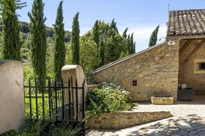 A stone building with a tiled roof, a stone wall, and a metal gate. - Gite Marie -Mas Paraloup (Lagorce)