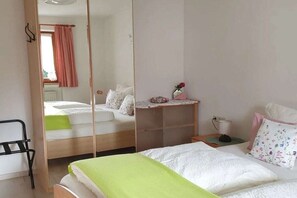 Ein Schlafzimmer mit einem Bett, einem Nachttisch, einem Spiegel und einem Stuhl.